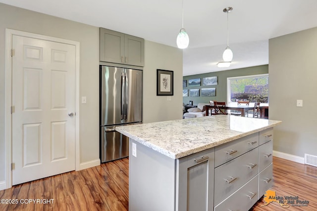 kitchen with stainless steel fridge, baseboards, gray cabinetry, and wood finished floors