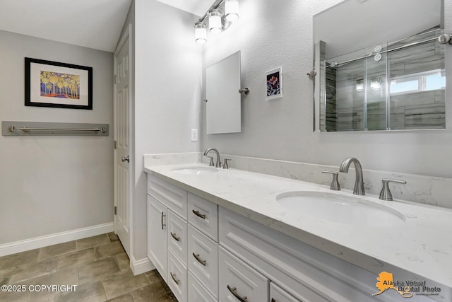 full bath with a shower stall, double vanity, baseboards, and stone finish floors