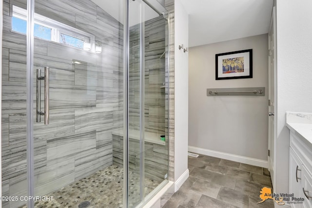 full bath with baseboards, a stall shower, and vanity