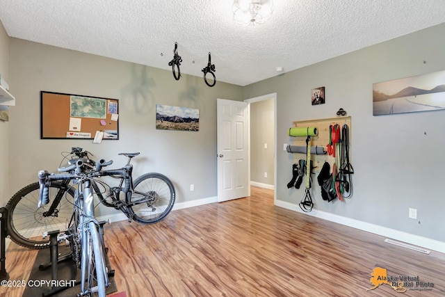 miscellaneous room with wood finished floors, a textured ceiling, and baseboards