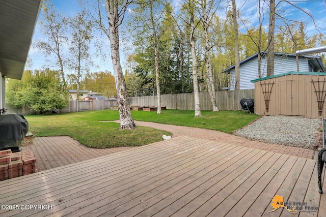 wooden deck with a shed, an outbuilding, and a grill
