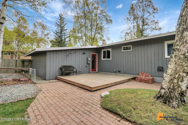 rear view of property with a deck, fence, a chimney, and a patio