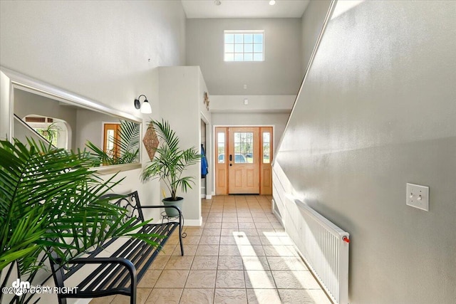 5672 Gooseberry Cir, Wasilla, AK 99654 - doorway to outside with radiator heating unit, a towering ceiling, baseboards, and light tile patterned flooring