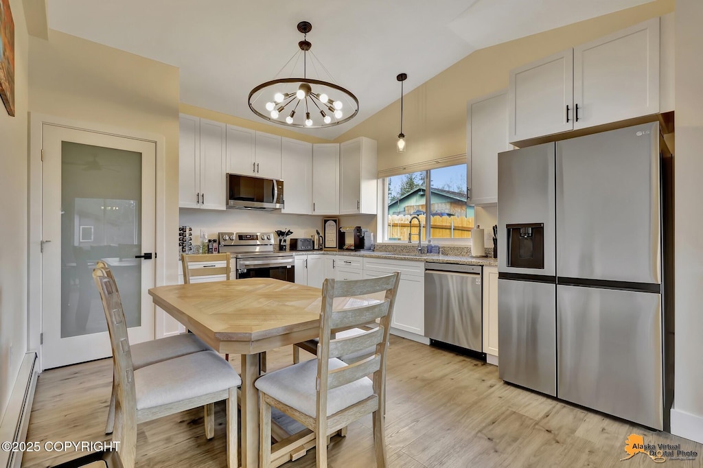 kitchen featuring an inviting chandelier, white cabinetry, appliances with stainless steel finishes, vaulted ceiling, and a baseboard radiator