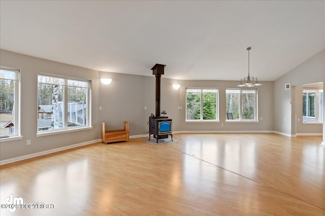 unfurnished living room with light wood-type flooring, a wood stove, and baseboards