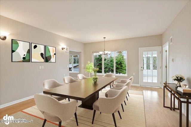 dining area featuring light wood-style flooring, baseboards, and a chandelier