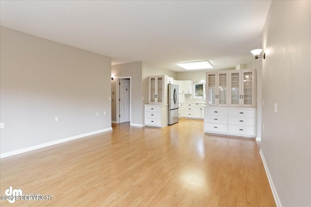 unfurnished living room featuring light wood-type flooring and baseboards