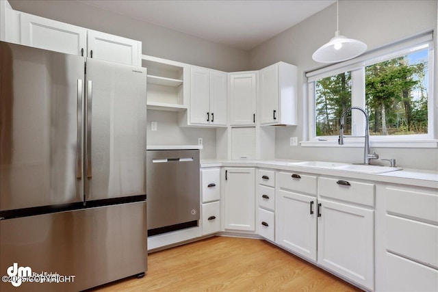 kitchen with appliances with stainless steel finishes, open shelves, a sink, and light countertops