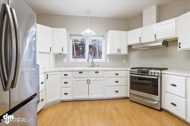 kitchen featuring appliances with stainless steel finishes, a sink, under cabinet range hood, light wood-style floors, and white cabinets
