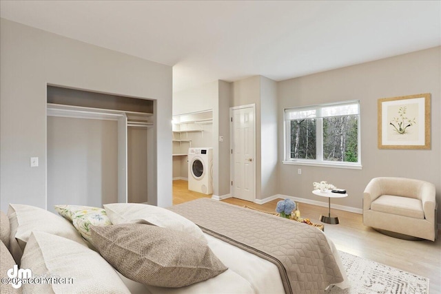 bedroom with washer / clothes dryer, light wood-type flooring, and baseboards