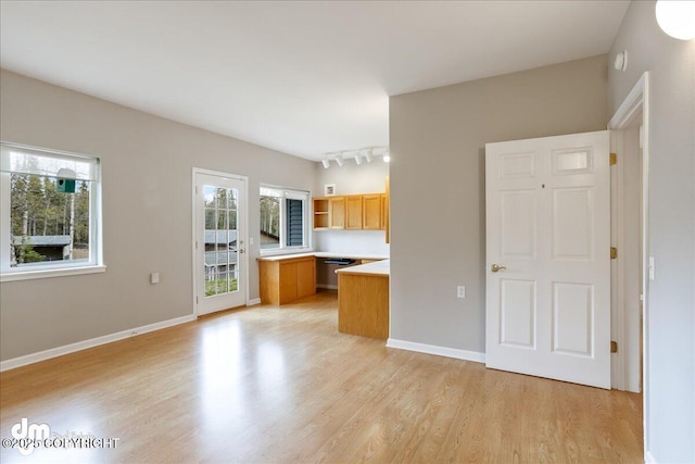 unfurnished living room featuring light wood-type flooring, rail lighting, and baseboards