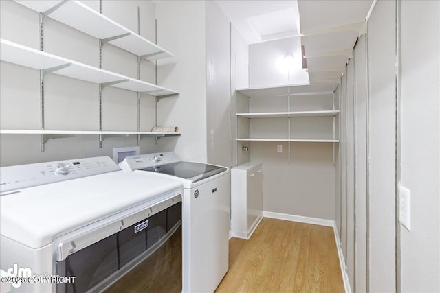 washroom featuring washer and clothes dryer, light wood-style floors, and baseboards