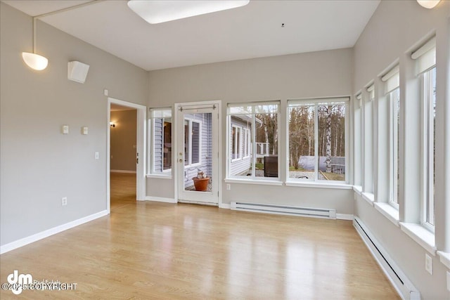 spare room featuring baseboard heating, wood finished floors, and plenty of natural light
