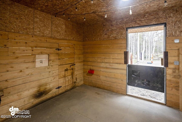 spare room with wood walls and concrete flooring