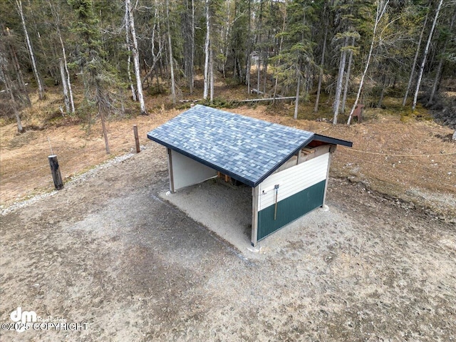 view of outdoor structure with a view of trees, an outbuilding, and driveway