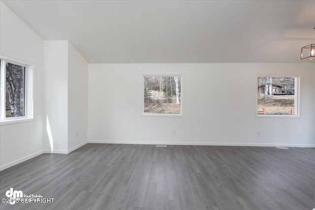 spare room with baseboards and wood finished floors