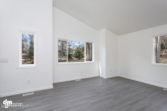 spare room featuring visible vents, dark wood-style floors, and a wealth of natural light
