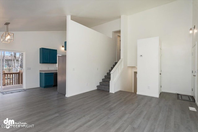 unfurnished living room with stairs, high vaulted ceiling, dark wood finished floors, and baseboards
