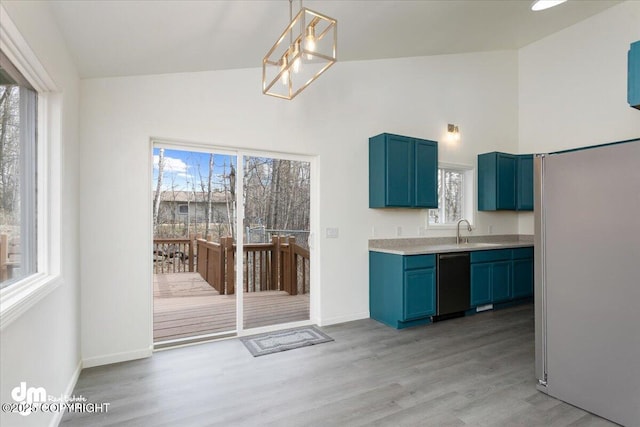 kitchen with blue cabinets, light countertops, high vaulted ceiling, dishwashing machine, and light wood-style flooring