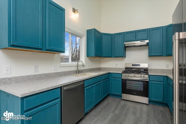 kitchen with a sink, stainless steel appliances, blue cabinets, and under cabinet range hood