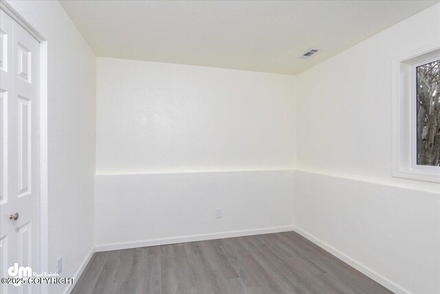 unfurnished room with visible vents, baseboards, and wood finished floors