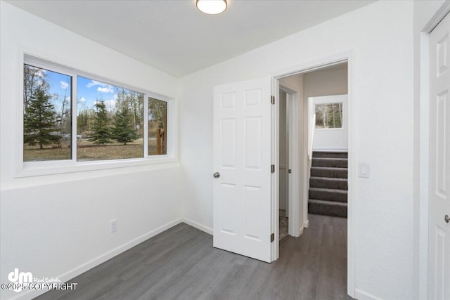 unfurnished bedroom with baseboards and dark wood-style floors