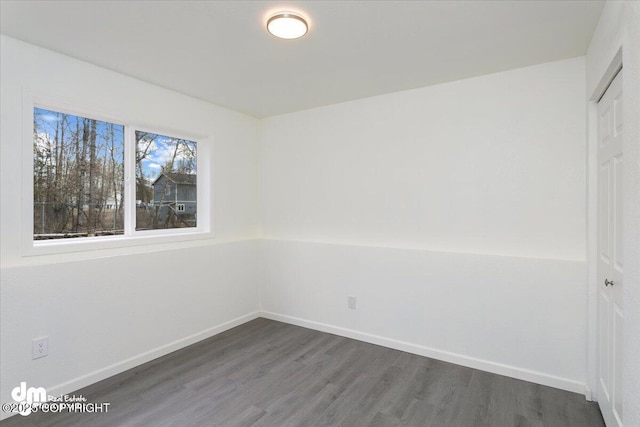 unfurnished room featuring baseboards and dark wood-type flooring