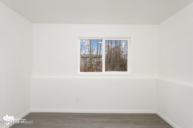 spare room with baseboards and wood finished floors