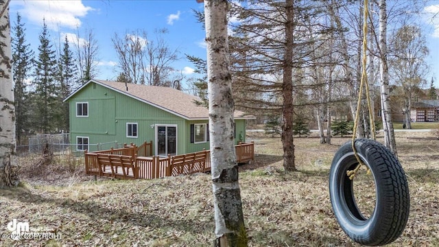 view of home's exterior with a shingled roof, fence, and a deck