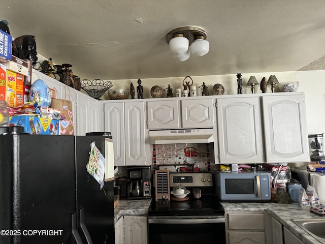 kitchen with under cabinet range hood, freestanding refrigerator, stainless steel range with electric stovetop, light countertops, and white cabinetry