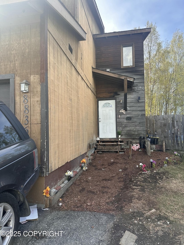 view of side of home with entry steps and fence