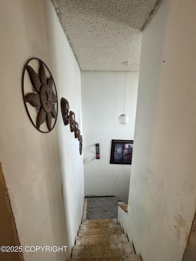 stairway featuring a textured ceiling and wood finished floors