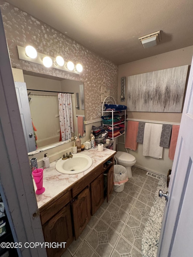 bathroom with wallpapered walls, toilet, a textured ceiling, vanity, and tile patterned flooring