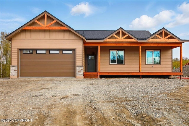 view of front facade featuring covered porch, board and batten siding, dirt driveway, a garage, and stone siding