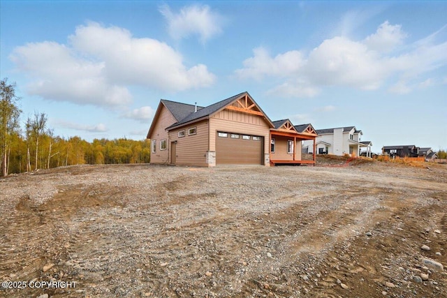view of side of property featuring a garage, board and batten siding, and dirt driveway
