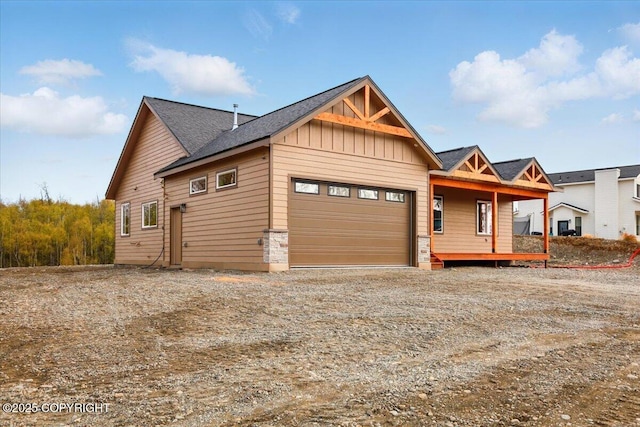 view of front of property featuring an attached garage, dirt driveway, and board and batten siding