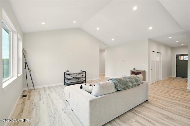 living area with baseboards, light wood-style flooring, lofted ceiling, and visible vents