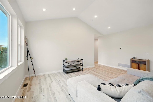 living area featuring visible vents, lofted ceiling, and light wood-type flooring
