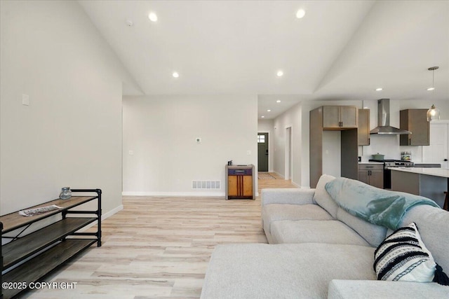 living area featuring recessed lighting, vaulted ceiling, light wood finished floors, and visible vents