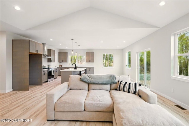 living area featuring visible vents, recessed lighting, light wood-style floors, and lofted ceiling