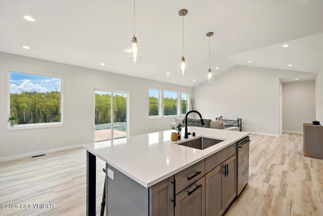 kitchen featuring visible vents, a sink, gray cabinetry, open floor plan, and light wood-style floors