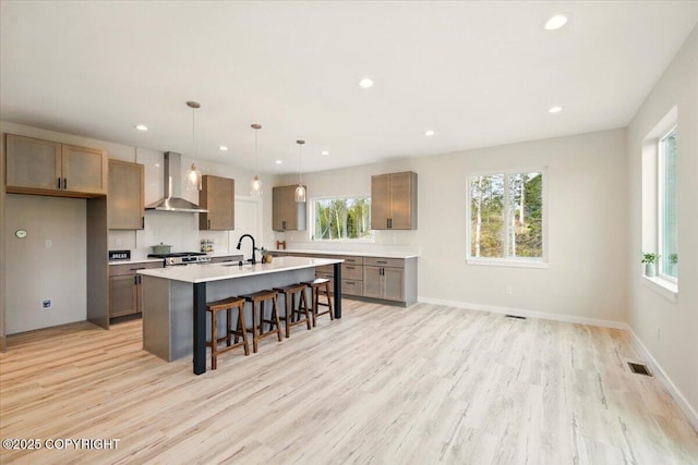 kitchen featuring a sink, light wood-style floors, recessed lighting, and wall chimney exhaust hood