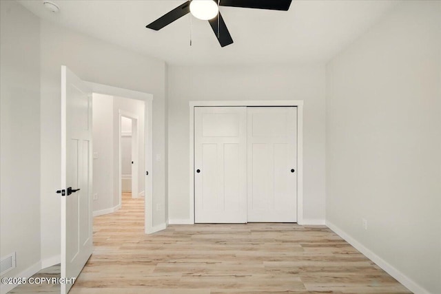 unfurnished bedroom with a closet, baseboards, ceiling fan, and light wood-style floors