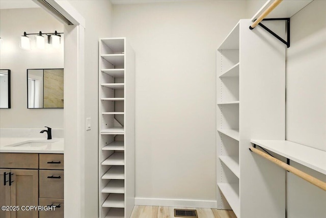 walk in closet featuring a sink, light wood-type flooring, and visible vents