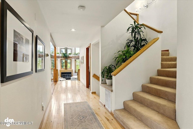corridor with stairway, light wood finished floors, and recessed lighting