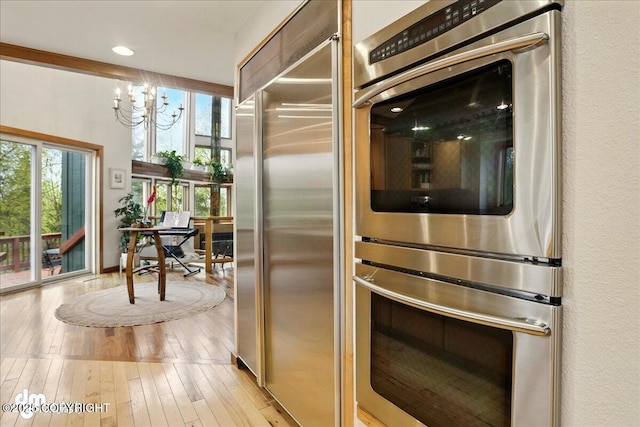 kitchen featuring appliances with stainless steel finishes, healthy amount of natural light, a chandelier, light wood-style floors, and recessed lighting