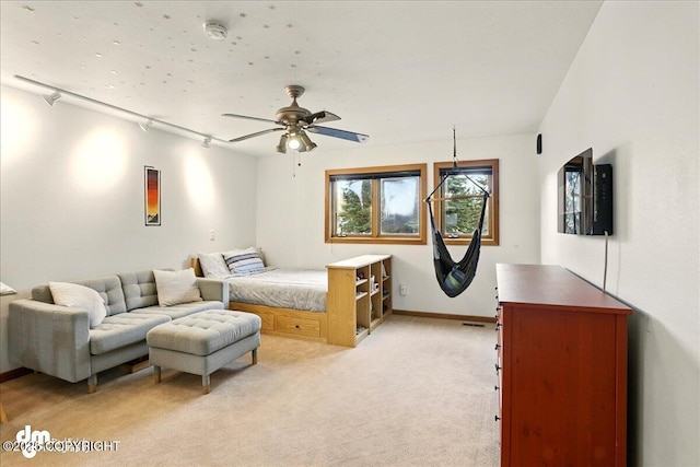 bedroom with light carpet, track lighting, baseboards, and ceiling fan