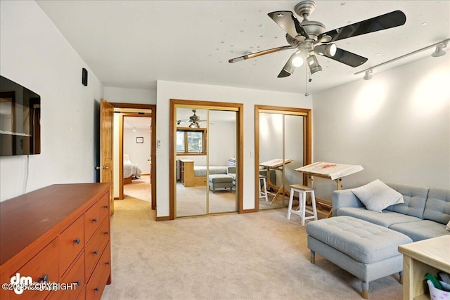 living area featuring a ceiling fan, light colored carpet, and rail lighting