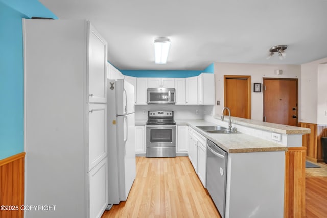 8515 Jewel Lake Rd # 25, Anchorage, AK 99502 - kitchen featuring appliances with stainless steel finishes, a sink, a peninsula, light countertops, and white cabinets