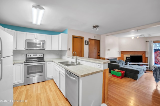 8515 Jewel Lake Rd # 25, Anchorage, AK 99502 - kitchen with appliances with stainless steel finishes, a sink, a peninsula, light wood-style floors, and light countertops